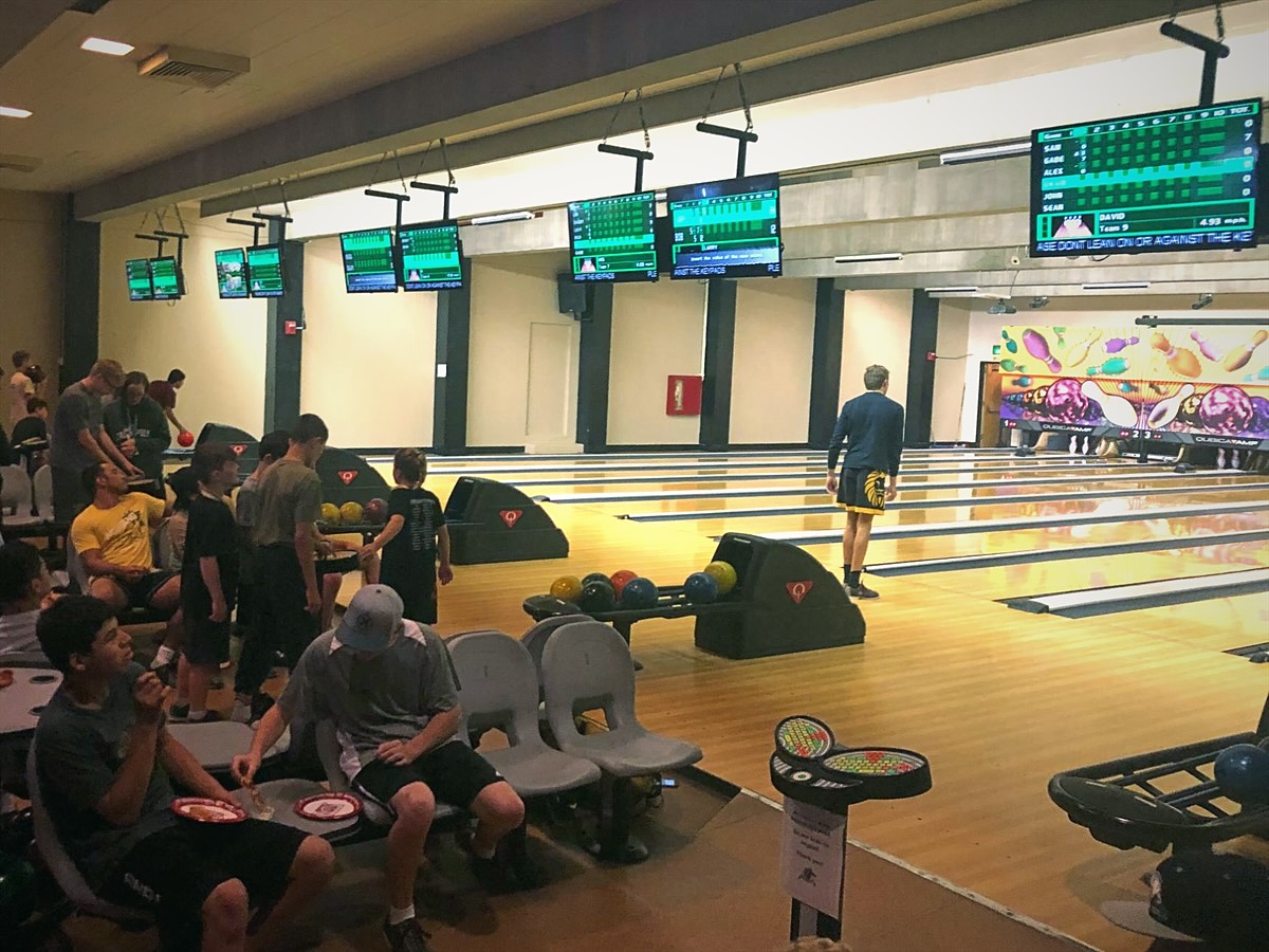 Campers bowling together on campus during an evening activity