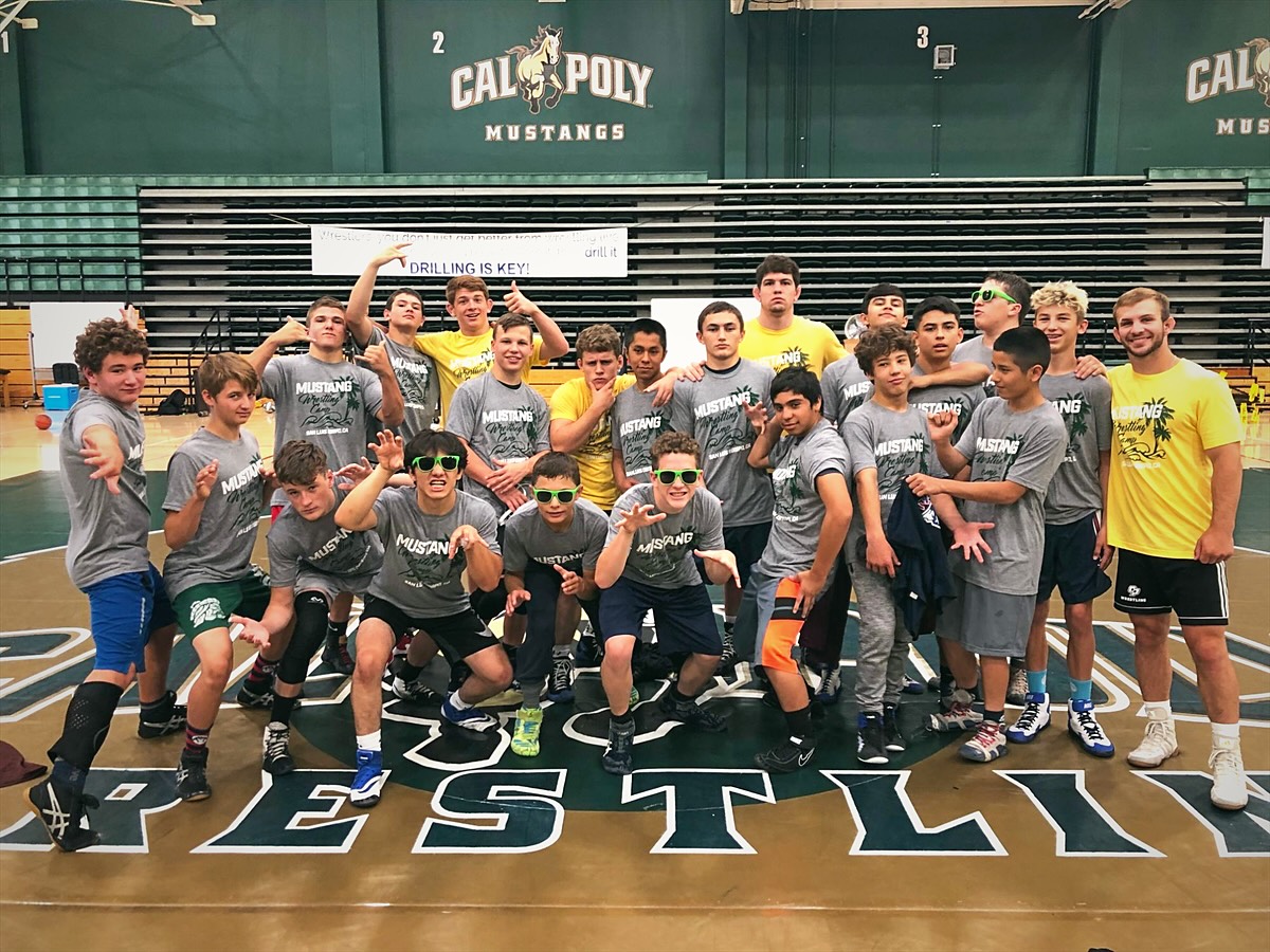 A group of campers in camp shirts clowning for a photo with their staff
