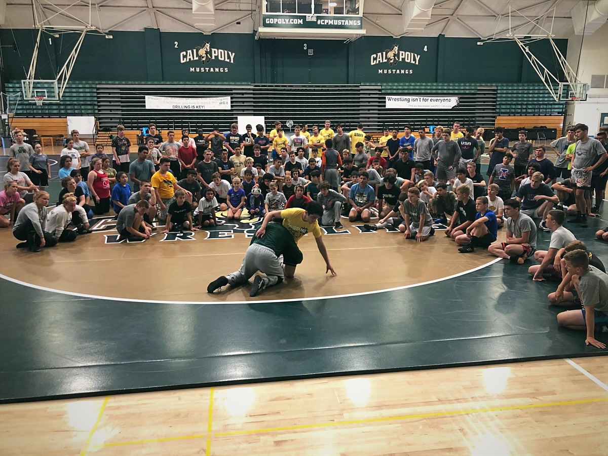 The whole camp watching a technique demonstration at center mat in a Cal Poly gym